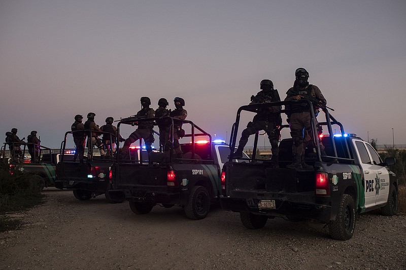 Mexican state police officers stand guard at dawn Thursday in trucks parked near the Rio Grandein Ciudad Acuna, Mexico.
(AP/Felix Marquez)