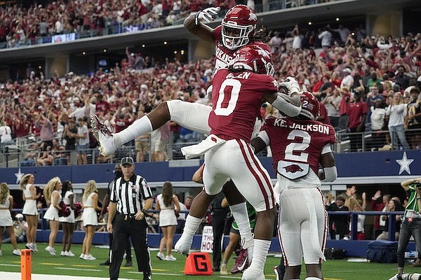 Arkansas wide receiver Trey Knox, top, AJ Green (0) and Ketron Jackson Jr. (2) celebrate a touchdown scored by Green in the first half of an NCAA college football game against Texas A&M in Arlington, Texas, Saturday, Sept. 25, 2021. (AP Photo/Tony Gutierrez)