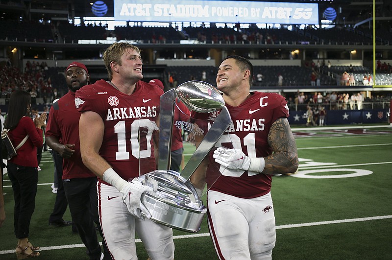 Arkansas linebackers Bumper Pool (10) and Grant Morgan (31) carry the Southwest Classic trophy off the field following a 20-10 victory over Texas A&M on Saturday, Sept. 25, 2021, in Arlington, Texas.