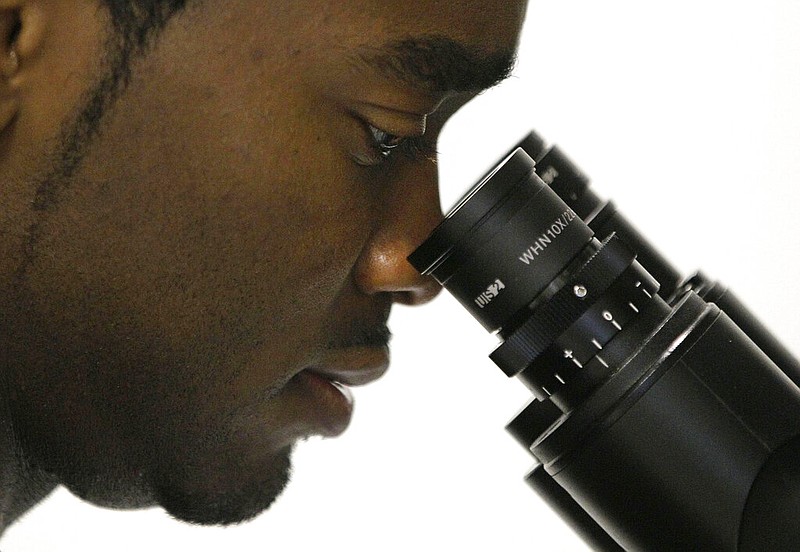 Christopher Smith, a doctoral student in biomedical engineering, looks through a microscope in a lab at the Johns Hopkins University medical campus in Baltimore in this Oct. 19, 2011, file photo. (AP/Patrick Semansky)