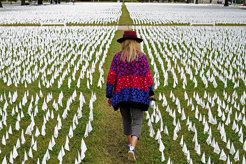 Artist Suzanne Brennan Firstenberg walks among thousands of white flags planted in remembrance of Americans who have died of covid-19 near Robert F. Kennedy Memorial Stadium in Washington in this Oct. 27, 2020, file photo. Firstenberg's temporary art installation, called "In America, How Could This Happen," included include an estimated 240,000 flags. (AP/Patrick Semansky)