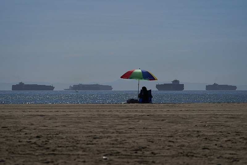 A person relaxes Friday on Seal Beach in California as container ships wait to dock at the Ports of Los Angeles and Long Beach. The cost for containers on such ships has risen sixfold from last year.
(AP/Jae C. Hong)