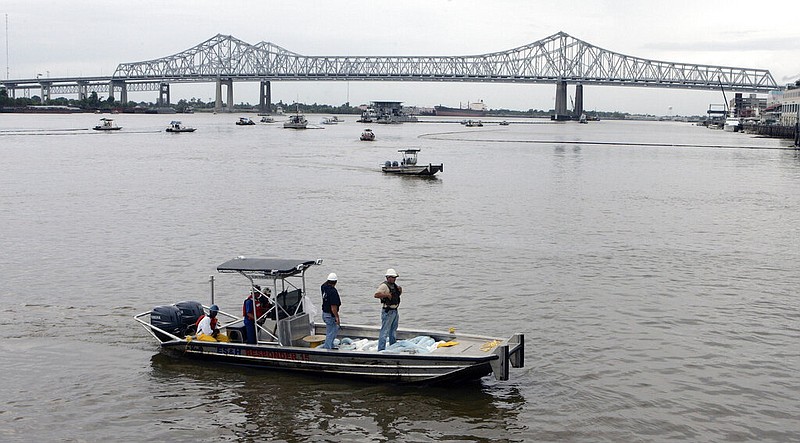 Workboats skim the river in an effort to clean up oil leaking from a damaged barge beneath the Mississippi River Bridge at the Port of New Orleans in this Aug. 1, 2008, file photo. (AP/Bill Haber)