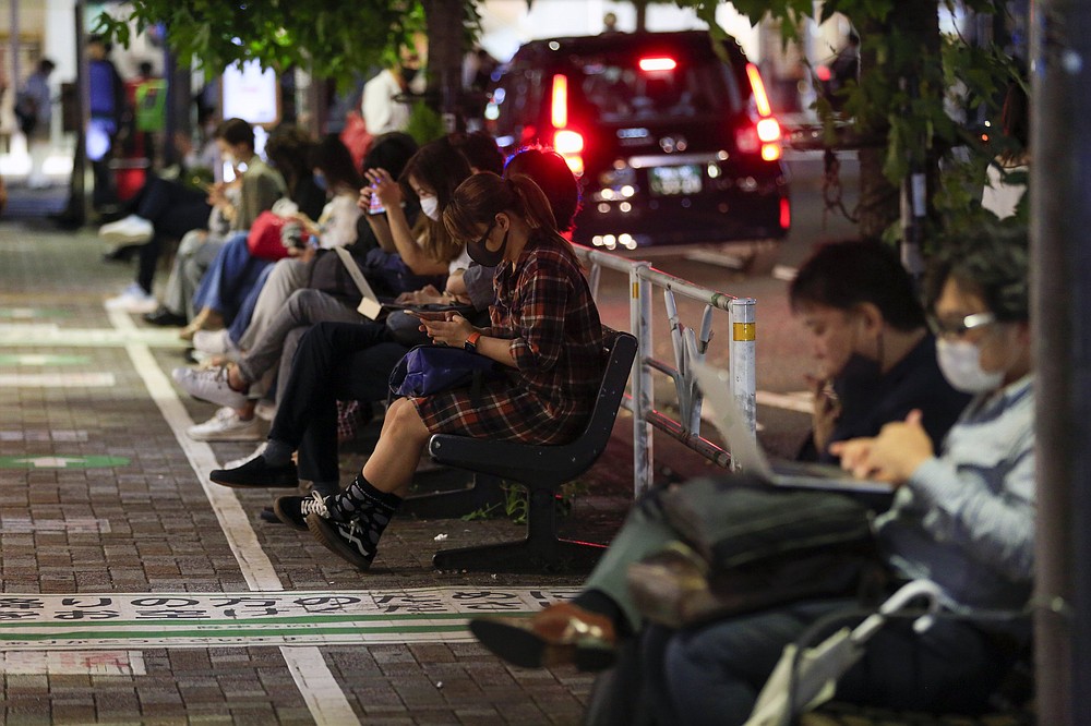 Des gens attendent devant une gare de Tokyo tôt vendredi après qu'un puissant séisme de magnitude 5,9 a secoué la région jeudi soir, arrêtant temporairement les trains et les métros.  Plus de photos sur arkansasonline.com/108tokyo/.  (AP/Kiichiro Sato)