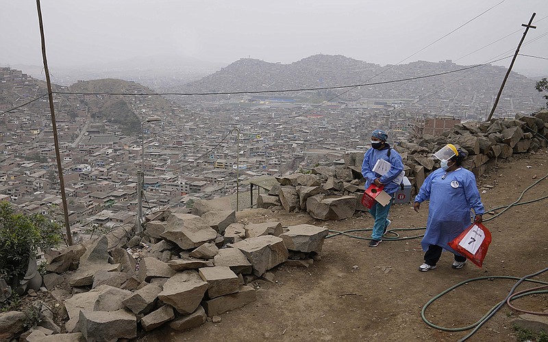 Nurses carry coolers of the Sinopharm covid-19 vaccine Wednesday as they go house to house to vaccinate residents in the Villa Maria del Triunfo neighborhood of Lima, Peru. The country is averaging 743 new infections a day, and slightly more than 45% of its population has been vaccinated.
(AP/Martin Mejia)