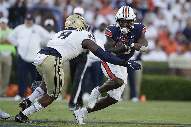 Auburn running back Tank Bigsby (4) carries the ball as he tries to get around Akron linebacker Jeslord Boateng (9) during the first half of an NCAA college football game Saturday, Sept. 4, 2021, in Auburn, Ala. (AP Photo/Butch Dill)