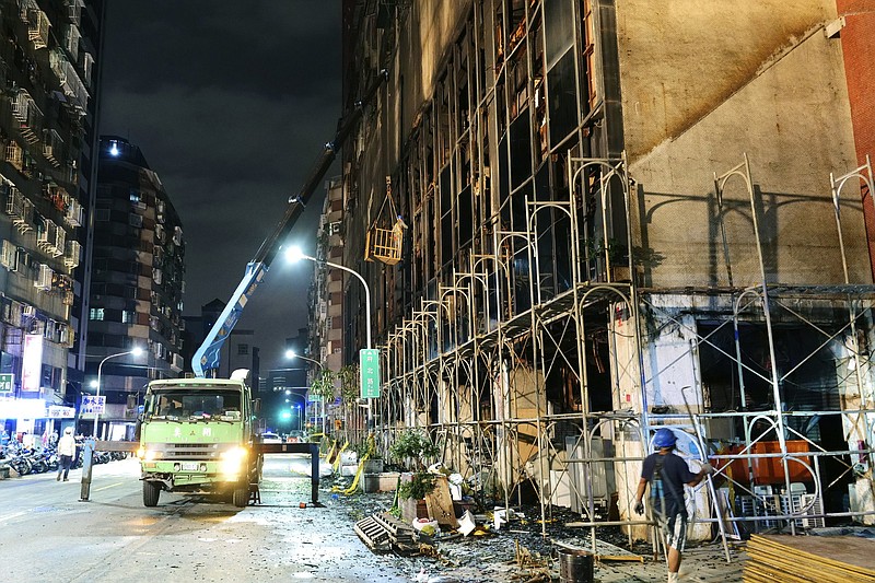 To prevent further hazard, workers break the glass windows of a previously burning building on Thursday in Kaohsiung, Taiwan.
(AP/Huizhong Wu)