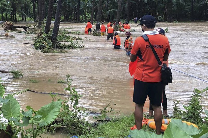 Rescuers help residents navigate floodwaters Tuesday in stormhit Brooke’s Point, Philippines.
(AP/Philippine Coast Guard)