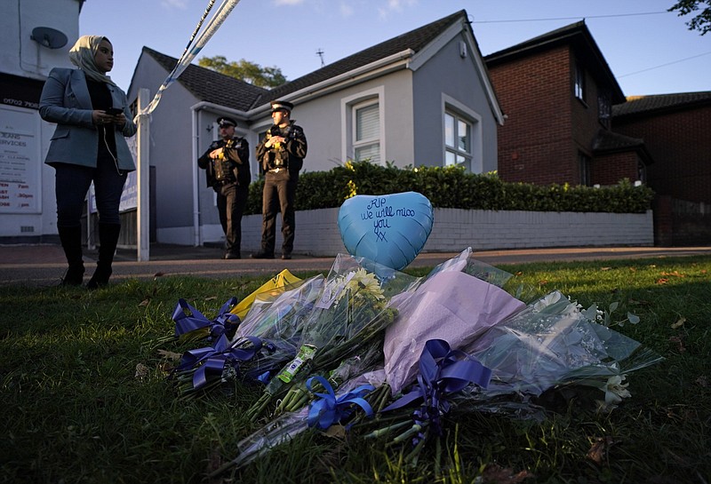 Floral tributes lie on the grass Friday as police officers block one of the roads leading to the Belfairs Methodist Church in Leigh-on-Sea, Essex, England, where British Conservative lawmaker David Amess died after being stabbed. Vidoe online at arkansasonline.com/1016stabbing/.
(AP/Alberto Pezzali)