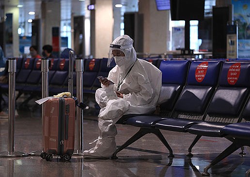 A passenger waits to board a flight in a full protective suit Friday at Tan Son Nhat airport in Ho Chi Minh City, Vietnam.
(AP/Hau Dinh)