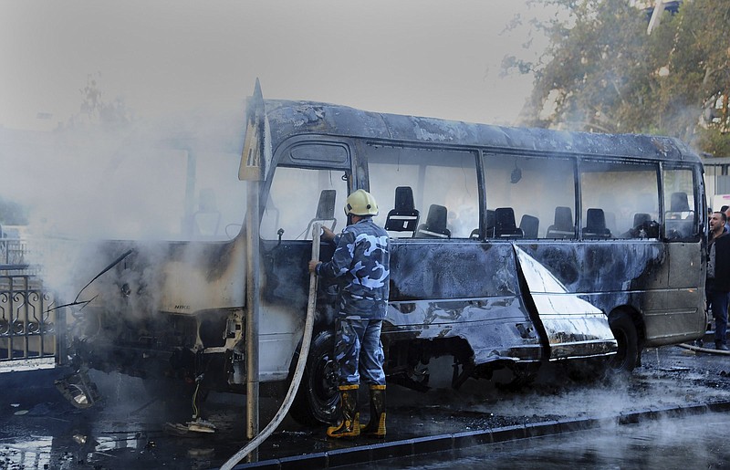 A firefighter extinguishes a bus fire Wednesday after a bombing in Damascus, Syria.
(AP/SANA)