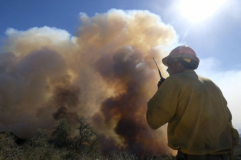 A firefighter monitors a wildfire earlier this month in Goleta, Calif. Worsening climate conditions have led intelligence agencies to develop assessments on the impact of climate change on migration of desperate people forced to leave their homes.
(AP/Ringo H.W. Chiu)