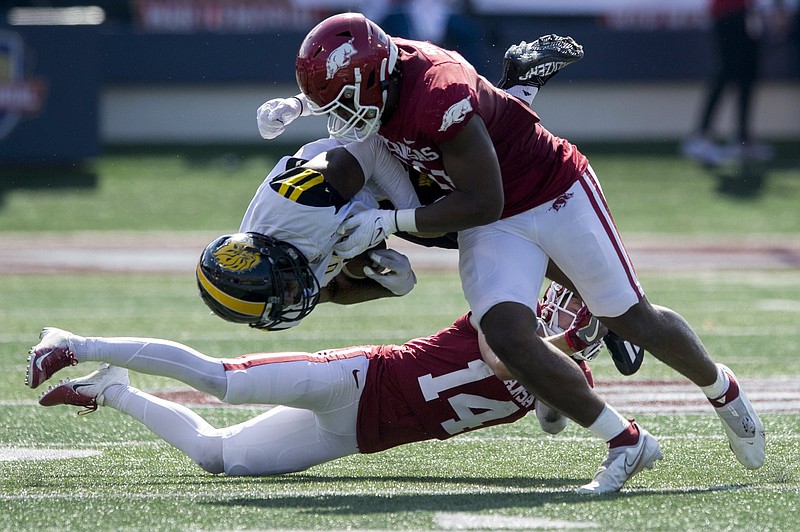 Arkansas defensive lineman Mataio Soli (top) and defensive back Nathan Parodi bring down Arkansas-Pine Bluff wide receiver Dalyn Hill during Saturday’s game at War Memorial Stadium in Little Rock. It was the Razorbacks’ first football game against an in-state opponent since 1944. More photos available at arkansasonline.com/1024HogsUAPB.
(Arkansas Democrat-Gazette/Stephen Swofford)