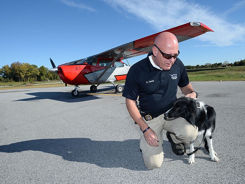 Robin Fields sits Thursday with Maverick at the Bentonville Municipal Airport. Fields has a long  background in law enforcement and was hired about a year ago to deploy Maverick at the airport to control the goose population.
(NWA Democrat-Gazette/Andy Shupe)