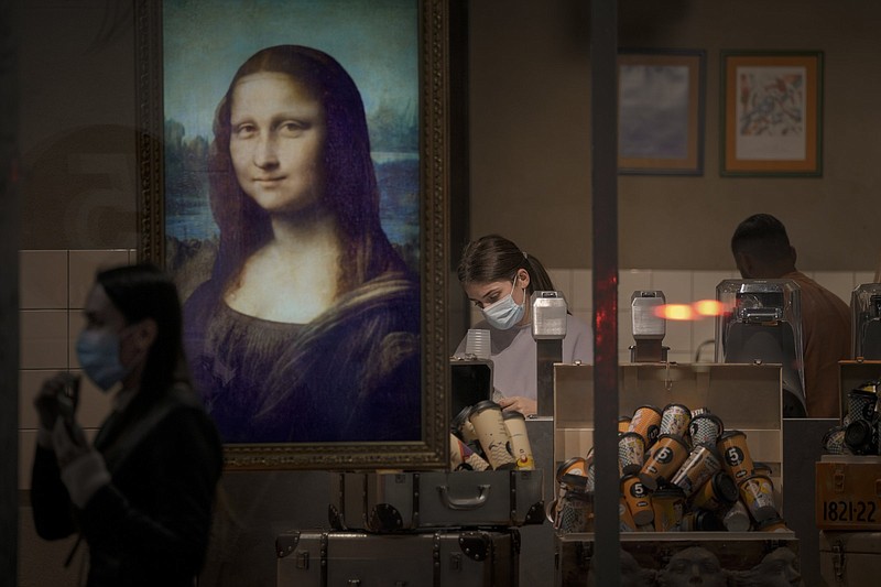 A display showing an animated depiction of Mona Lisa hangs in a coffee shop window Sunday as an employee cleans up shortly after closing hours in Bucharest, Romania. In an attempt to curb a surge of covid-19 infections and relieve pressure on hospitals, authorities approved tighter restrictions set to take effect today.
(AP/Vadim Ghirda)