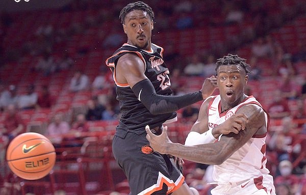 Arkansas guard Davonte Davis (right) passes past East Central's Shemar Smith during an exhibition game Sunday, Oct. 24, 2021, in Fayetteville.