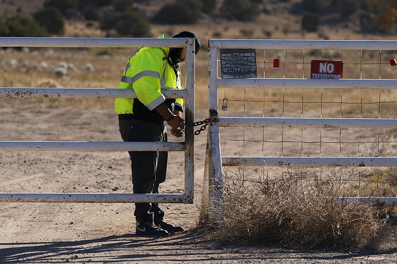 A security guard manning the entrance to the Bonanza Creek Ranch film set locks the gate after turning away workers who came to pick up equipment in Santa Fe, N.M., Monday, Oct. 25, 2021. A camera operator told authorities that Alec Baldwin had been careful with weapons on the set of the film "Rust." Baldwin shot and killed a cinematographer with a gun he'd been told was safe to use, court records released Sunday show. (AP Photo/Jae C. Hong)