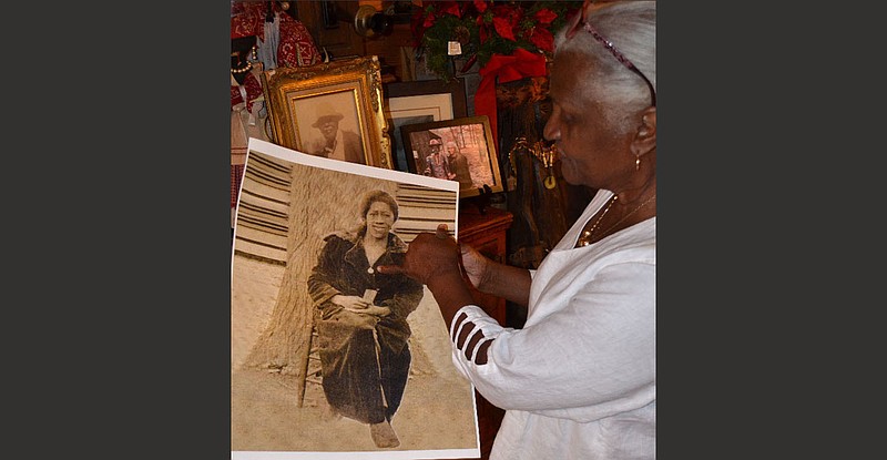 Caroline Williams holds up a large photo about which she says, "This is my dad's grandmother sitting barefoot on an auction block with a slave collar around her neck and a sale ticket in her hand." 
(Special to The Commercial/Richard Ledbetter)