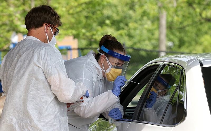 Nurse Tonya Green (center) uses a swab to take an oral covid-19 test of a patient as nursing student Shaughn Barge (left) looks on at the drive-up covid-19 testing location at New Life Church in North Little Rock in this April 24, 2020, file photo. The testing location was a collaboration of Natural State Laboratories, Sniffle Health and Arkansas Surgical Center. (Arkansas Democrat-Gazette/Thomas Metthe)