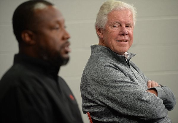 Lance Harter (right), head coach of Arkansas women's cross country and track and field, smiles Tuesday, Nov. 2, 2021, as he listens to Chris Johnson, associate head coach, during a press conference to announce Harter's 2023 retirement and that Johnson will succeed him as head coach at the Broyles Athletics Center in Fayetteville.