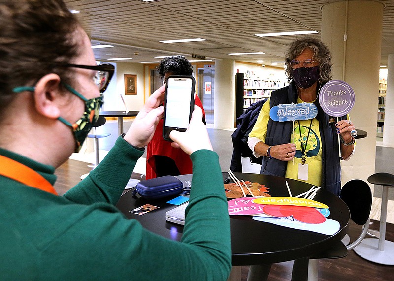 Karen Guthrie poses as Olivia Domba takes her photo after Guthrie received her covid-19 booster shot on Wednesday, Nov. 3, 2021, at the Central Arkansas Library System Main Library in Little Rock. (Arkansas Democrat-Gazette/Thomas Metthe)