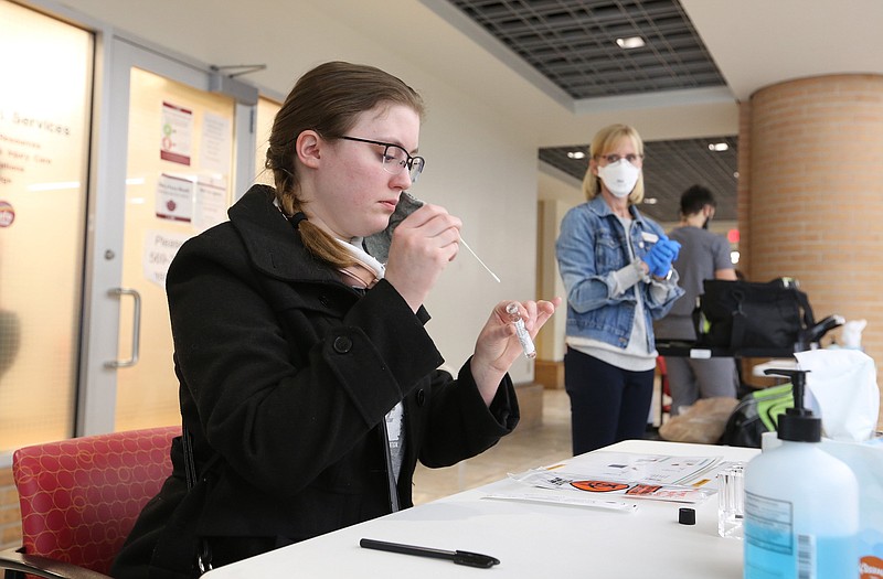 Rebekah White, a graduate student at the University of Arkansas at Little Rock, puts her swab in a container after taking a covid-19 self-test as nurse Tracy England (right) looks on at the UALR Donaghey Student Center in this Thursday, Jan. 14, 2021, file photo. (Arkansas Democrat-Gazette/Thomas Metthe)