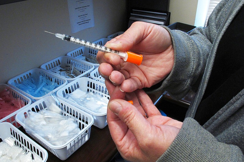 A nurse for eastern Indiana's Fayette County holds a syringe at the county courthouse in Connersville, Ind., in this March 24, 2016, file photo. The syringe is one of those provided to intravenous drug users taking part in the county's state-approved needle exchange program. Intravenous drug users who share needles can spread hepatitis C, and the exchange program was an attempt to help battle an infection that had nearly tripled between 2010 and 2017. (AP/Rick Callahan)