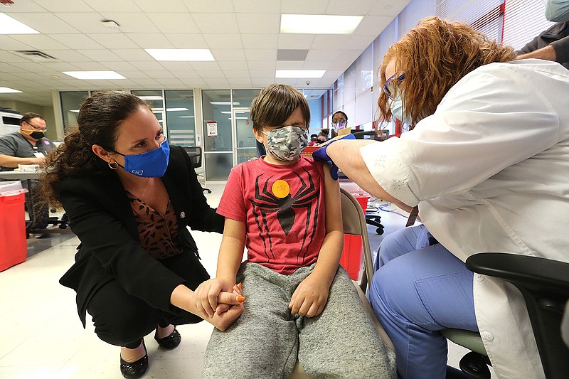 George "CJ" Hudson (center), 8, holds his mother, Ashley's, hand while getting his covid-19 vaccine from physician assistant Janet Rader (right) on Tuesday, Nov. 9, 2021, at the UAMS Vaccine Clinic in Little Rock. (Arkansas Democrat-Gazette/Thomas Metthe)