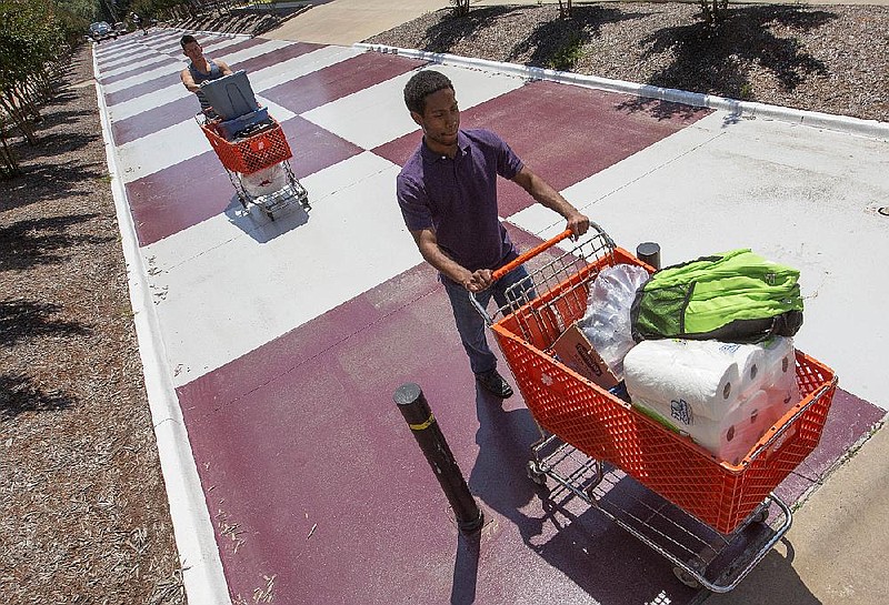 Christopher Davis (right) and Miguel Valderrama, then both Donaghey Scholars at the University of Arkansas at Little Rock, use shopping carts to move out of the dorm rooms on campus in this May 2017 file photo. Valderrama was among the university's international students, hailing from Lima, Peru. (Arkansas Democrat-Gazette/Benjamin Krain)