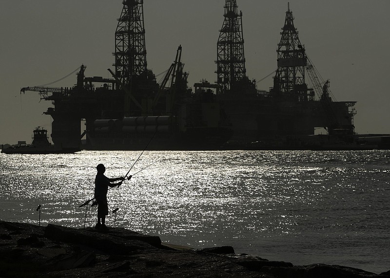 A man fishes near docked oil drilling platforms in Port Aransas, Texas. The U.S. Interior Department on Wednesday auctioned vast oil reserves in the Gulf of Mexico estimated to hold up to 1.1 billion barrels of crude.
(AP)