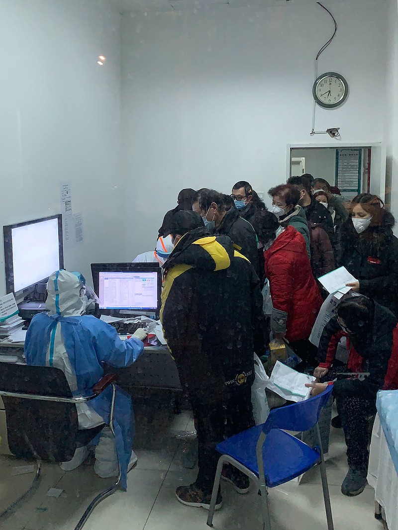 People stand at a health care worker’s desk while waiting for medical attention at a hospital in Wuhan, China, on Jan. 28, 2020.
(The New York Times/Chris Buckley)