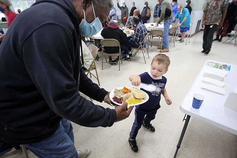 Volunteer Calvin Ledbetter, 4, gives out silverware to diners Thursday during the Little Rock Compassion Center’s Thanksgiving dinner in Little Rock.
(Arkansas Democrat-Gazette/Thomas Metthe)