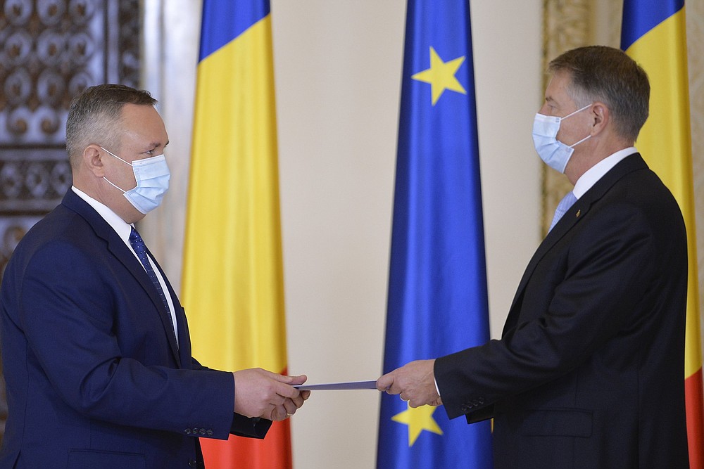 Newly appointed Prime Minister Nicolae Ciuca (left) hands Romanian President Klaus Iohannis a signed oath of office during Thursday’s swearing-in ceremony in Bucharest.
(AP/Alexandru Dobre)