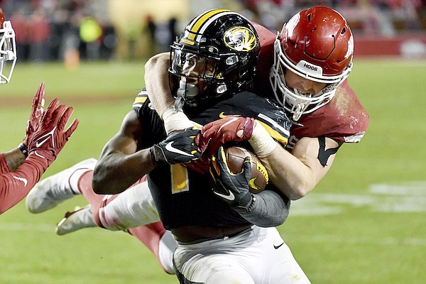 Arkansas defensive back Bumper Pool (10) tackles Missouri running back Tyler Badie (1) during the second half of an NCAA college football game Friday, Nov. 26, 2021, in Fayetteville, Ark. (AP Photo/Michael Woods)