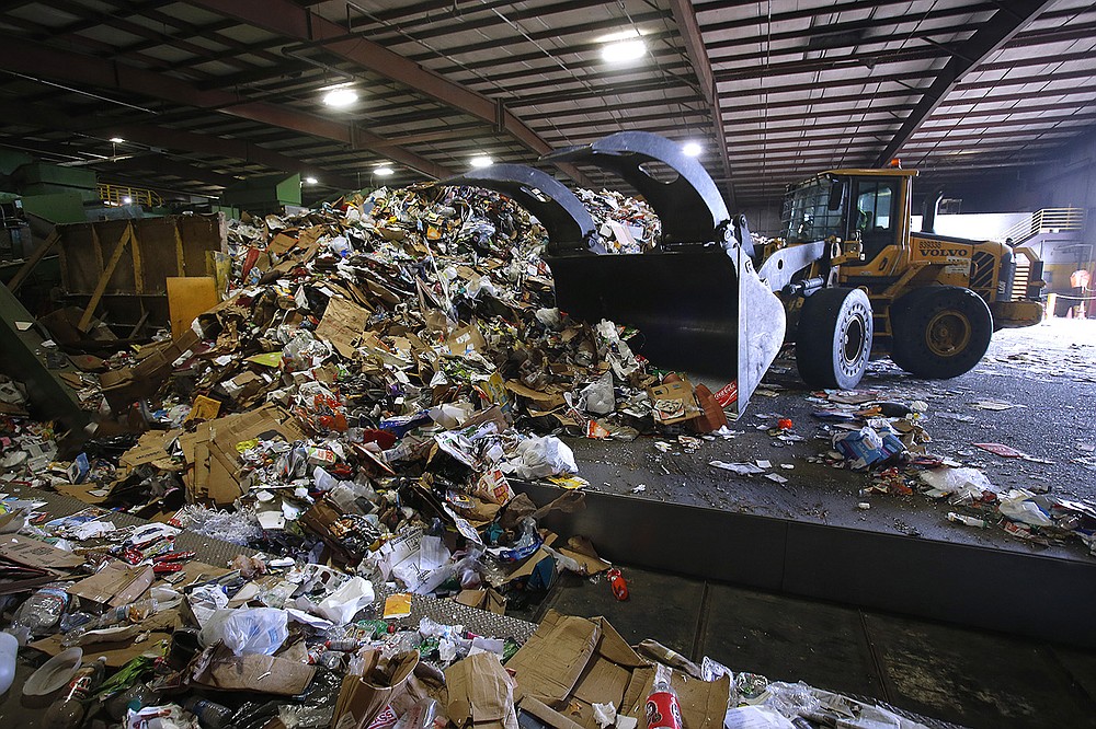 Recyclable materials are pushed onto a conveyor belt to be sorted Wednesday at the Waste Management Little Rock Recycling Facility.
(Arkansas Democrat-Gazette/Thomas Metthe)