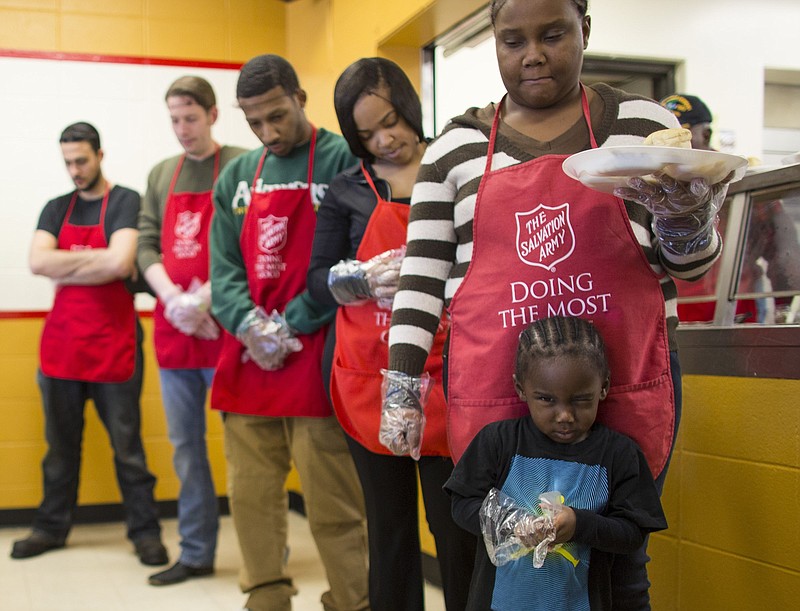 Salvation Army volunteers bow their heads in prayer before serving a pre-covid Christmas dinner in Little Rock. Almost half of all Americans said they regularly took a moment before meals to give thanks, according to a 2017 poll by The Washington Post and the Kaiser Family Foundation.
(Arkansas Democrat-Gazette file photo)