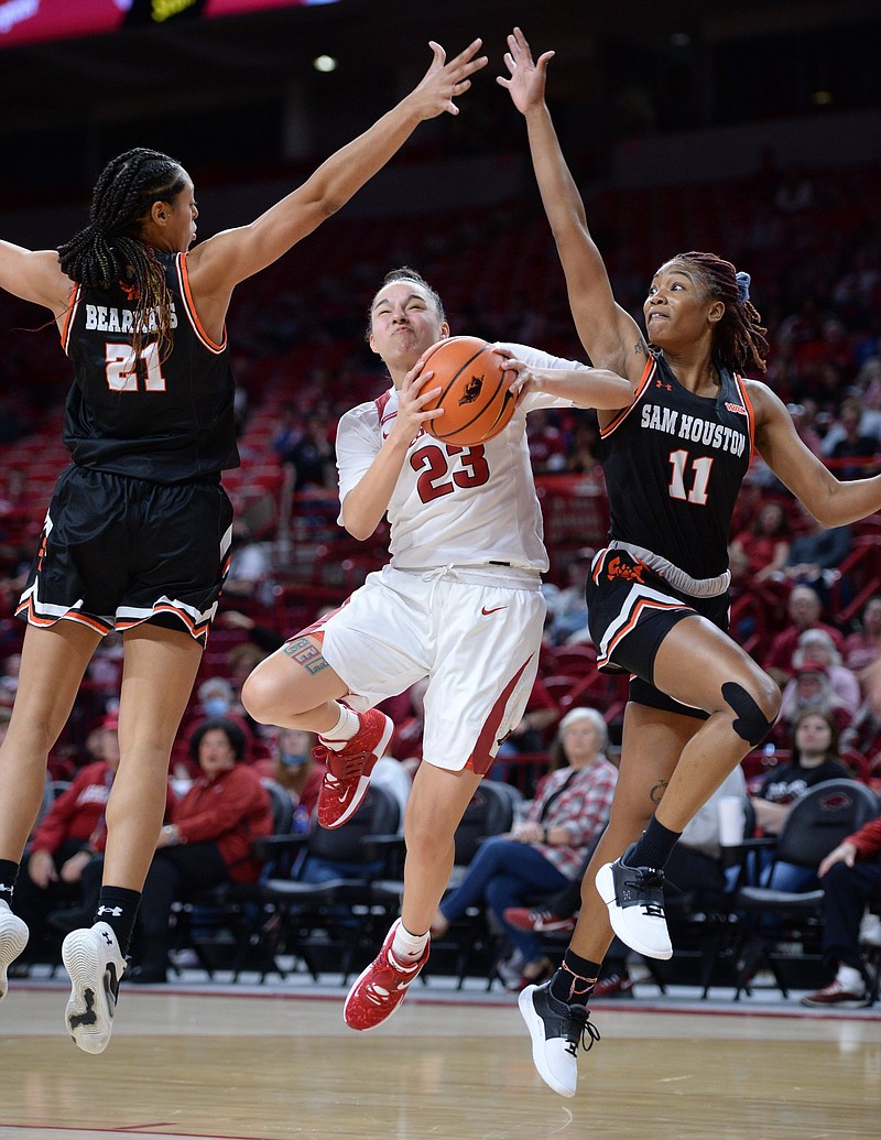 Arkansas guard Amber Ramirez (23) leaps to score Saturday, Nov. 27, 2021, as she is pressured by Sam Houston forward Madelyn Batista (21) and guard Courtney Cleveland (11) during the first half of play in Bud Walton Arena. Visit nwaonline.com/211128Daily/ for today's photo gallery..(NWA Democrat-Gazette/Andy Shupe)