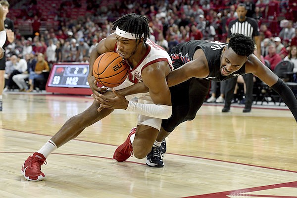 Arkansas guard Stanley Umude (0) and Pennsylvania guard Jonah Charles (2) fight for a loose ball during the second half of an NCAA college basketball game Sunday, Nov. 28, 2021, in Fayetteville, Ark. (AP Photo/Michael Woods)