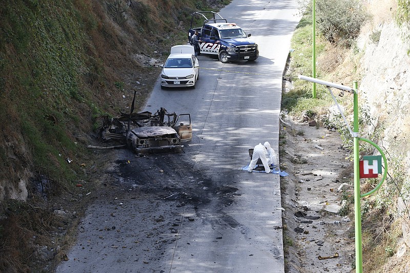Forensic investigators work at an area where a burned-out car was found after a gang rammed several vehicles into a prison and escaped with nine inmates Wednesday in Tula, Mexico.
(AP/Ginnette Riquelme)