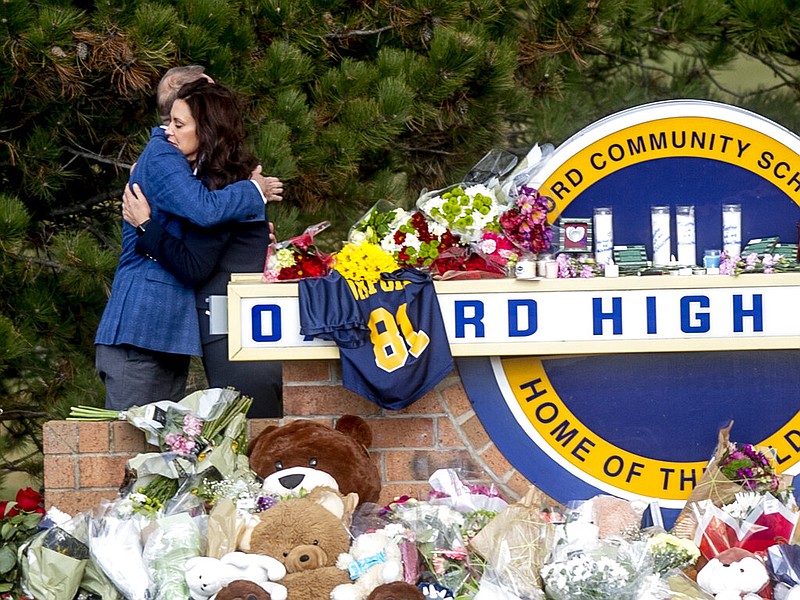 Gov. Gretchen Whitmer embraces Oakland County Executive Dave Coulter as the two leave flowers and pay their respects Thursday morning, Dec. 2, 2021 at Oxford High School in Oxford, Mich. (Jake May/The Flint Journal via AP)