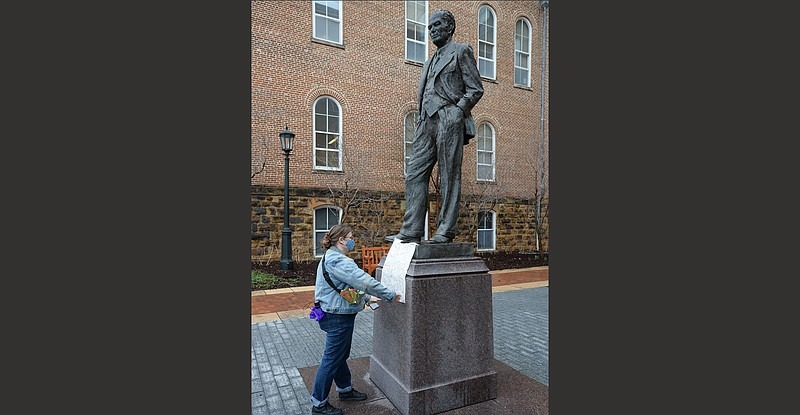 Sarah Campau, a graduate student at the University of Arkansas, Fayetteville straightens a sign on March 13 at a statue of J. William Fulbright during an anti-racism rally on campus. The late U.S. senator’s civil rights record spawned calls this year to remove the statue from campus.
(NWA Democrat-Gazette/Andy Shupe)
