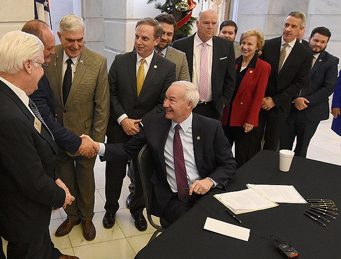 Gov. Asa Hutchinson shakes hands with legislators Thursday after signing the tax-cut bills at the state Capitol in Little Rock. Hutchinson said the cuts give more people more control over their money and their lives. More photos at arkansasonline.com/1210lege/.
(Arkansas Democrat-Gazette/Staci Vandagriff)