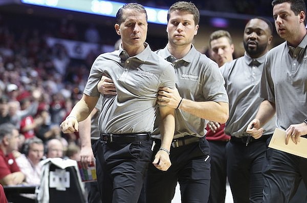 Arkansas coach Eric Musselman (left) is escorted off the floor by Michael Musselman, his son and the Razorbacks' assistant director of basketball operations, during a game against Oklahoma on Saturday, Dec. 11, 2021, in Tulsa.