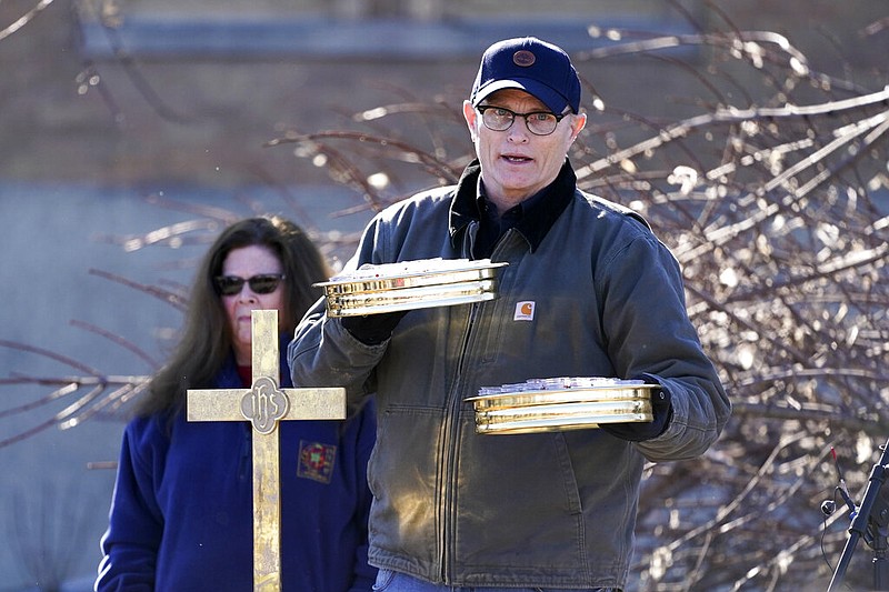 Dr. Milton West, senior minister of First Christian Church, holds communion trays during an outdoor service in Mayfield, Ky., on Sunday, Dec. 12, 2021. The service was held in the parking lot of the tornado-damaged church. (AP/Mark Humphrey)