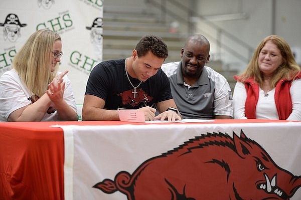 Greenland's JJ Hollingsworth (center) signs Wednesday, Dec. 15, 2021, alongside his mother, Amy Johnson (from left); father, Jaye Johnson; and grandmother, Janet Hollingsworth during a signing ceremony in Dee Lee Gymnasium in Greenland. Hollingsworth signed to play football with Arkansas.