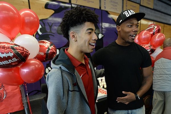 Fayetteville seniors Isaiah Sategna (left) and Mani Powell laugh Wednesday, Dec. 15, 2021, while posing for photographs during a signing ceremony in the school's cafeteria. Sategna and Powell signed to play football with Arkansas.
