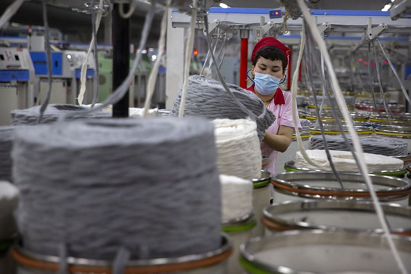 A worker gathers cotton yarn at a textile plant in China’s Xinjiang region last spring. China on Friday urged the U.S. “to immediately correct its mistake” after the Senate passed a bill barring imports from the region unless businesses can prove the items were produced without forced labor.
(AP/Mark Schiefelbein)