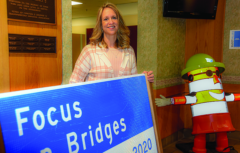 Melissa Wilbers poses next to familiar signage and figures at the Missouri Department of Transportation's District Headquarters building from where she's retiring after 30 years of service to the state of Missouri. Wilbers will now be teaching remotely for the Missouri S&T in Rolla and working part time elsewhere. (Julie Smith/News Tribune)