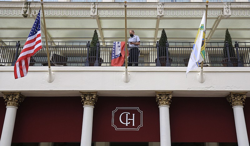A hotel employee hangs the Arkansas flag Monday May 17, 2021at the Capital Hotel in downtown Little Rock.