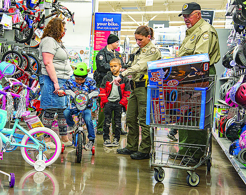 A Cole County deputy and Sheriff's Posse help a child pick out a bike for Christmas during Operation Toys at Walmart Supercenter on Saturday morning, Dec. 18, 2021.  The annual event pairs a local law enforcement or corrections officer with a child to provide them with presents under the tree for Christmas.